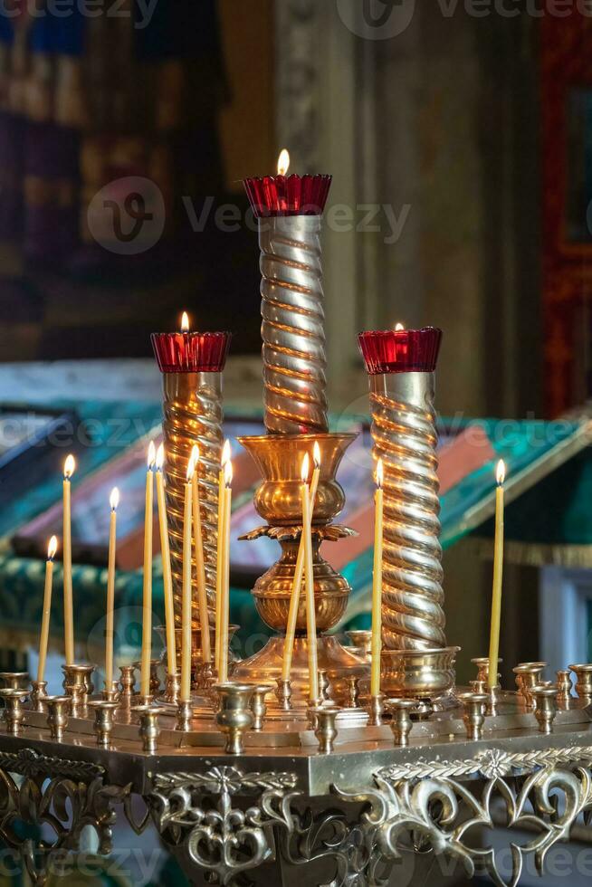 Church candles are burning on a large golden vintage candlestick in the orthodox church. Christian faith and traditions. Theme of faith and God, religion and traditions. photo