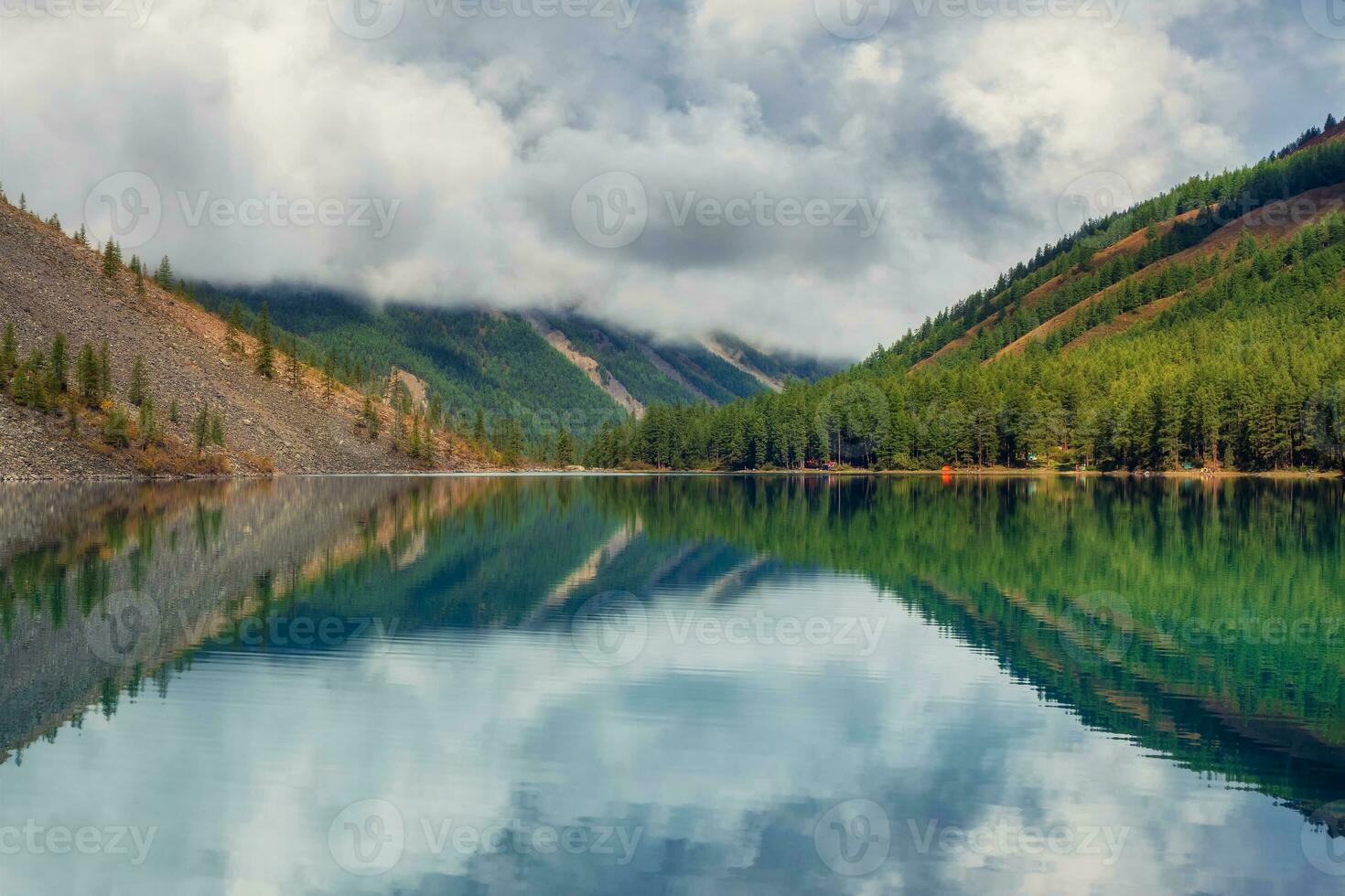 Morning view of lake in the mountains surrounded by fir trees and mountain peaks. Mystical morning landscape with fog over the lake. photo