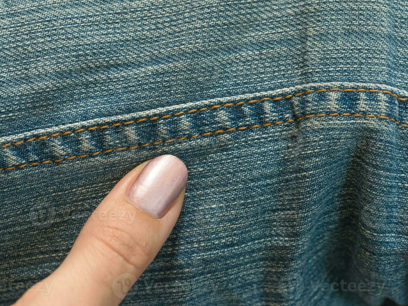 the finger points to the stitched jeans photo