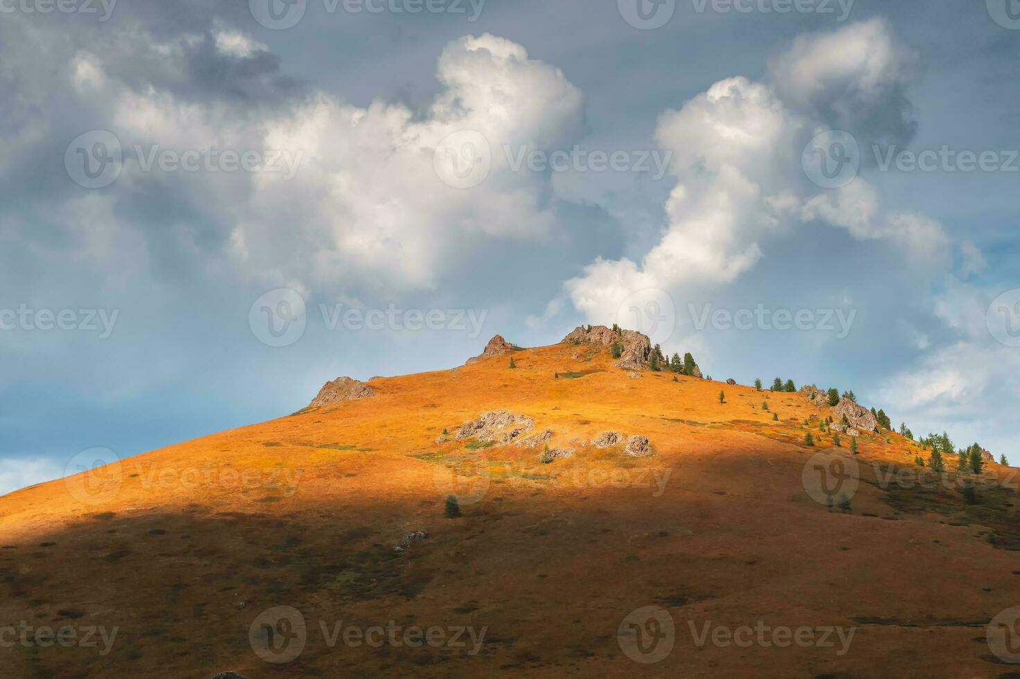 Amazing mountain landscape with cone  rock in golden sunlight under beautiful white clouds. Nature background of rocky mountain and green cedar forest. Colorful sunny backdrop with high rocky mountain photo