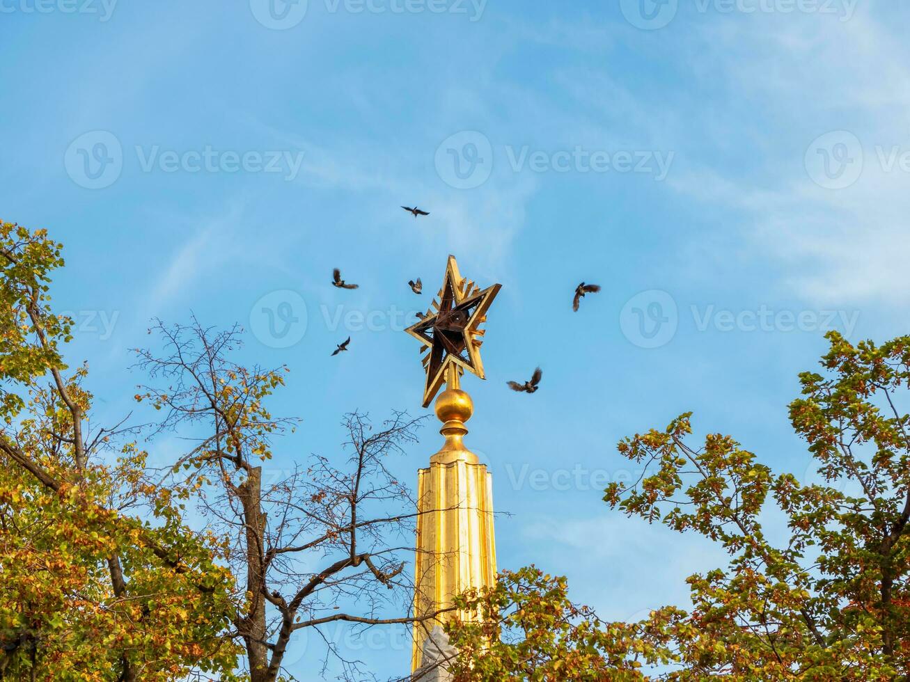 Black birds fly around the spire, VDNH, Moscow. photo