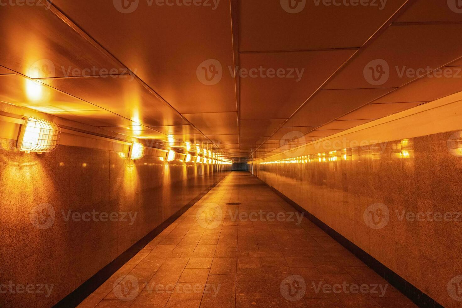 Empty underground passage illuminated with yellow light. photo