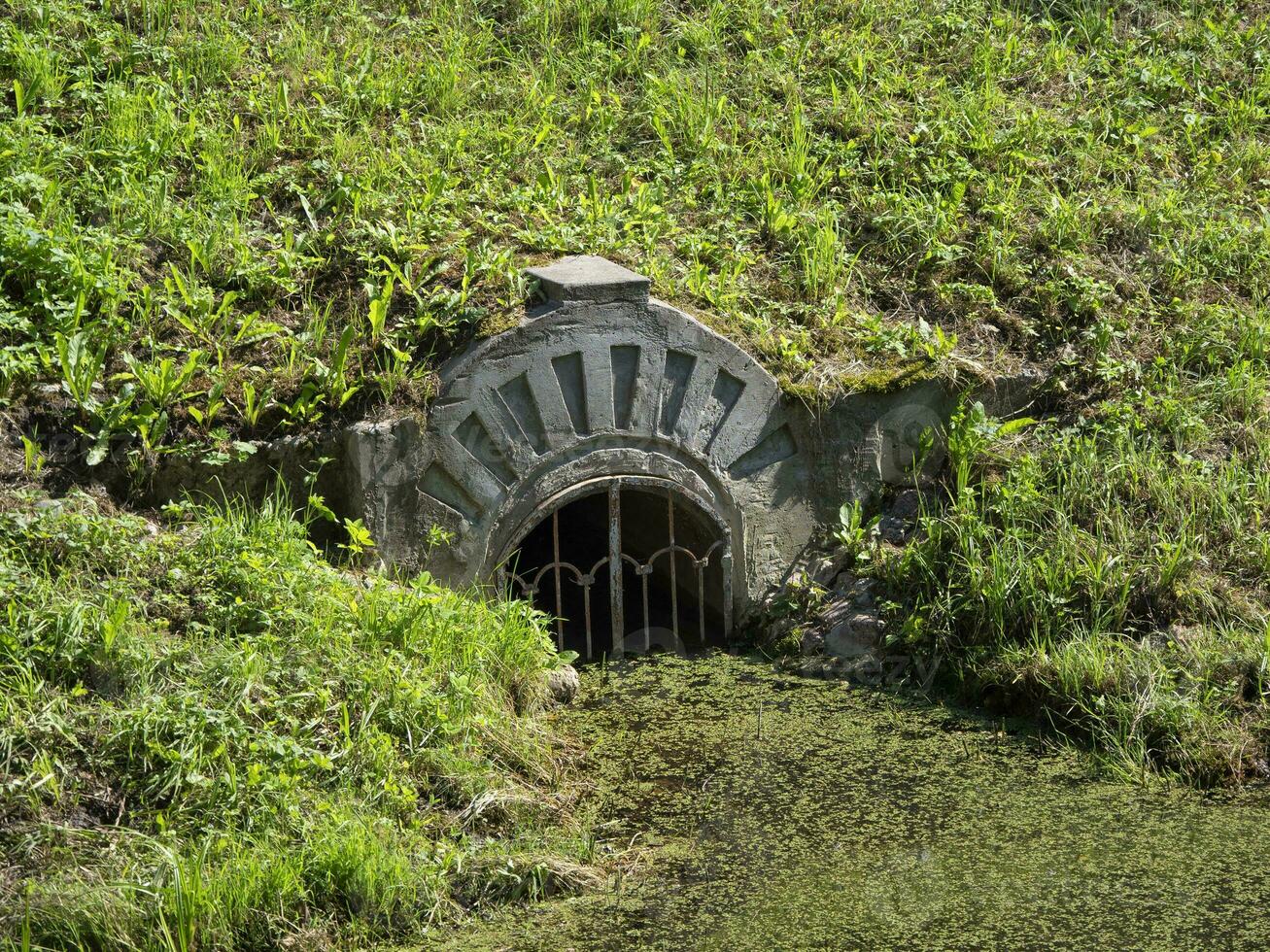 agua fluir en el estanque. el Entrada es cerrado por un fuerte metal parrilla foto