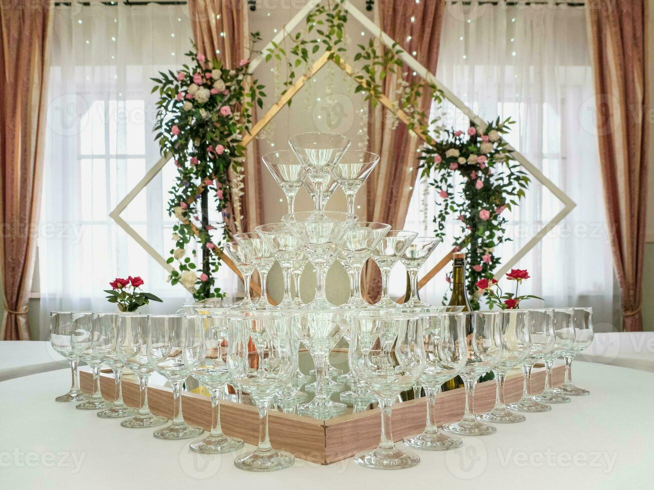 Empty wine glasses on a table are a pyramid. Beautiful wedding ceremony indoors. photo