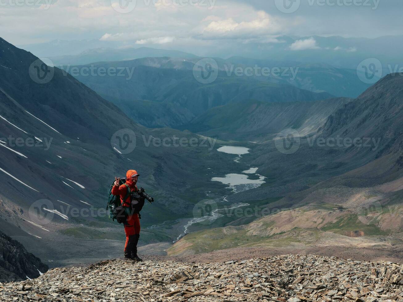 Happy travel photographer. Travel photographer take a victory finger gesture in high mountains. Travel freelancer blogger lifestyle, concept adventure voyage outdoor. photo