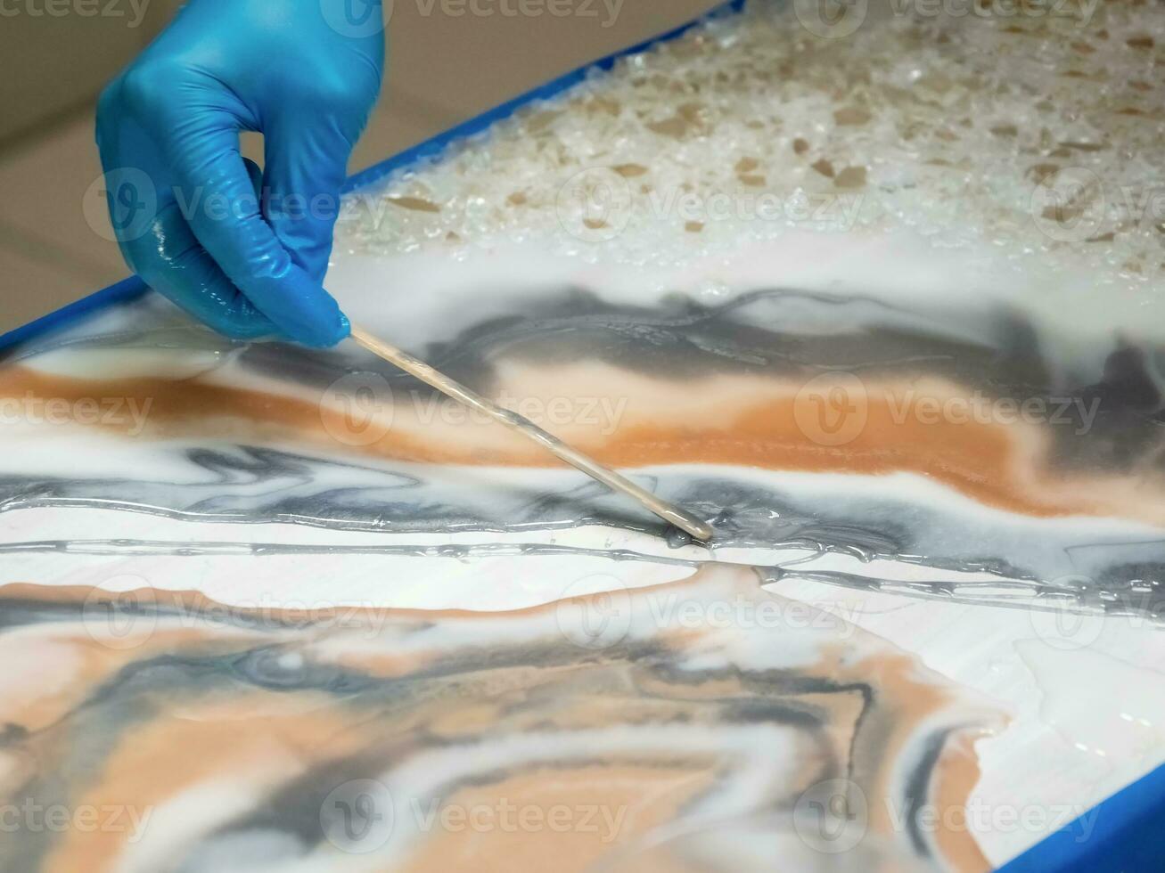 Technology process of creating a painting in style resin art, woman works with epoxy in studio,  makes a wooden stand with the image. Epoxy resin art painting space. photo