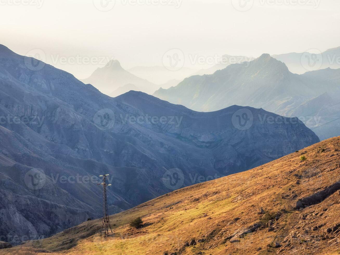 Network of wires and telegraph poles on the autumn foggy mountain hills. Atmospheric mountain foggy landscape in Dagestan. photo