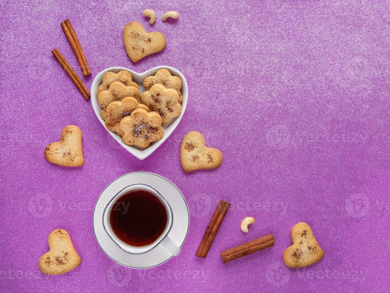 Festive ginger cookies with cinnamon in the shape of hearts are laid out on a pink background. Top view. photo