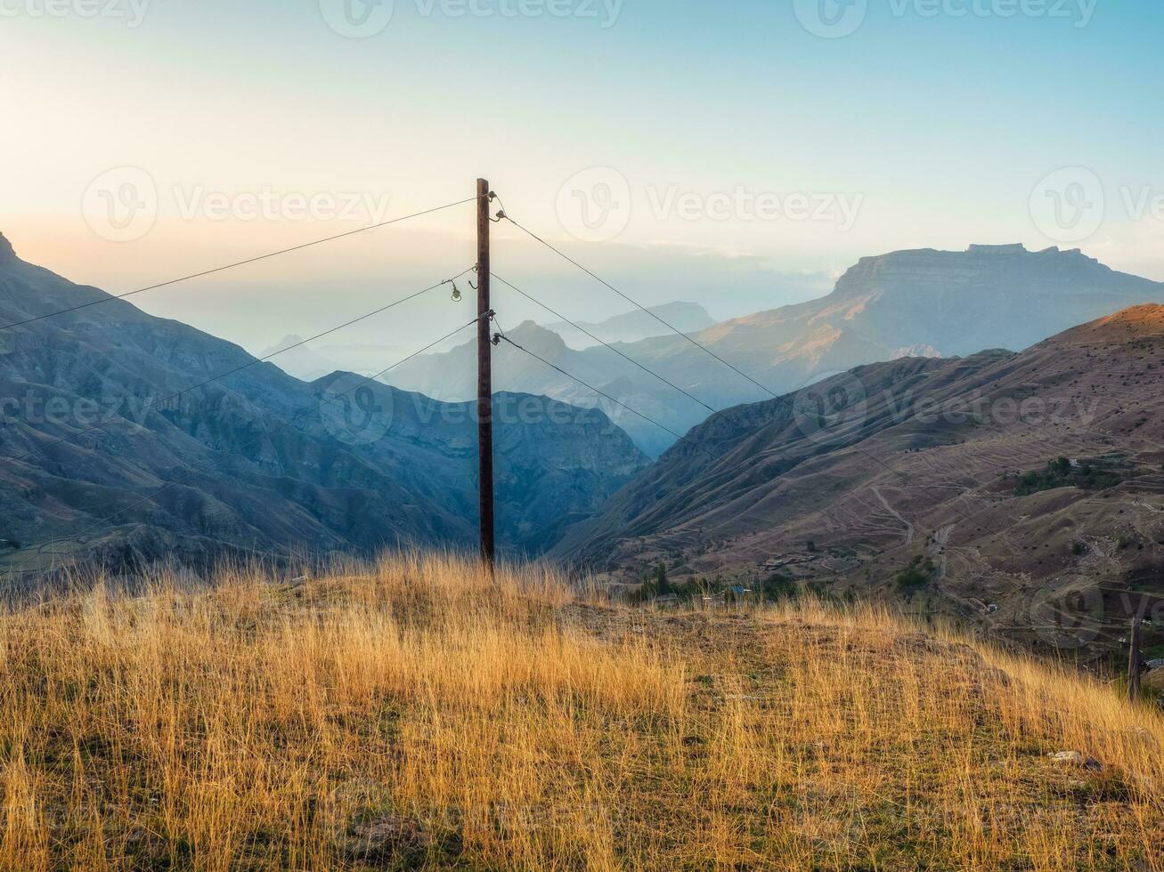 Network of wires and telegraph poles on the autumn foggy mountain hills. Atmospheric mountain foggy landscape in Dagestan. photo
