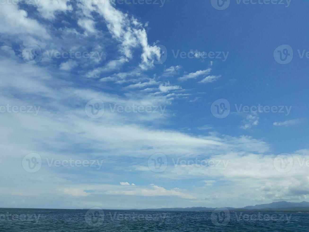 el azul cielo con blanco nubes encima el vasto Oceano foto