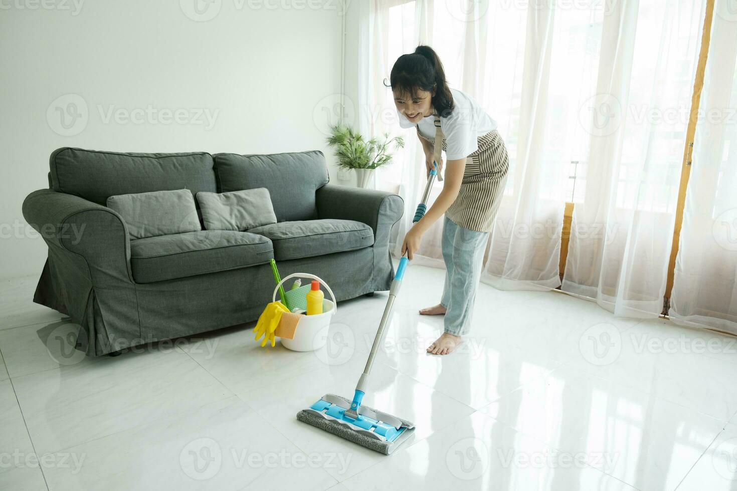 Young woman cleaning floor using mop at home. photo