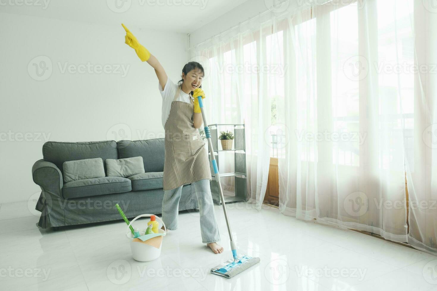 Young woman having fun while cleaning at home. photo