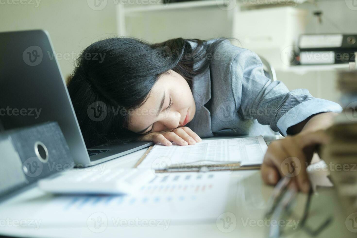 Young asian Business woman tired woman sleeping on desk with laptop at workplace alone. photo