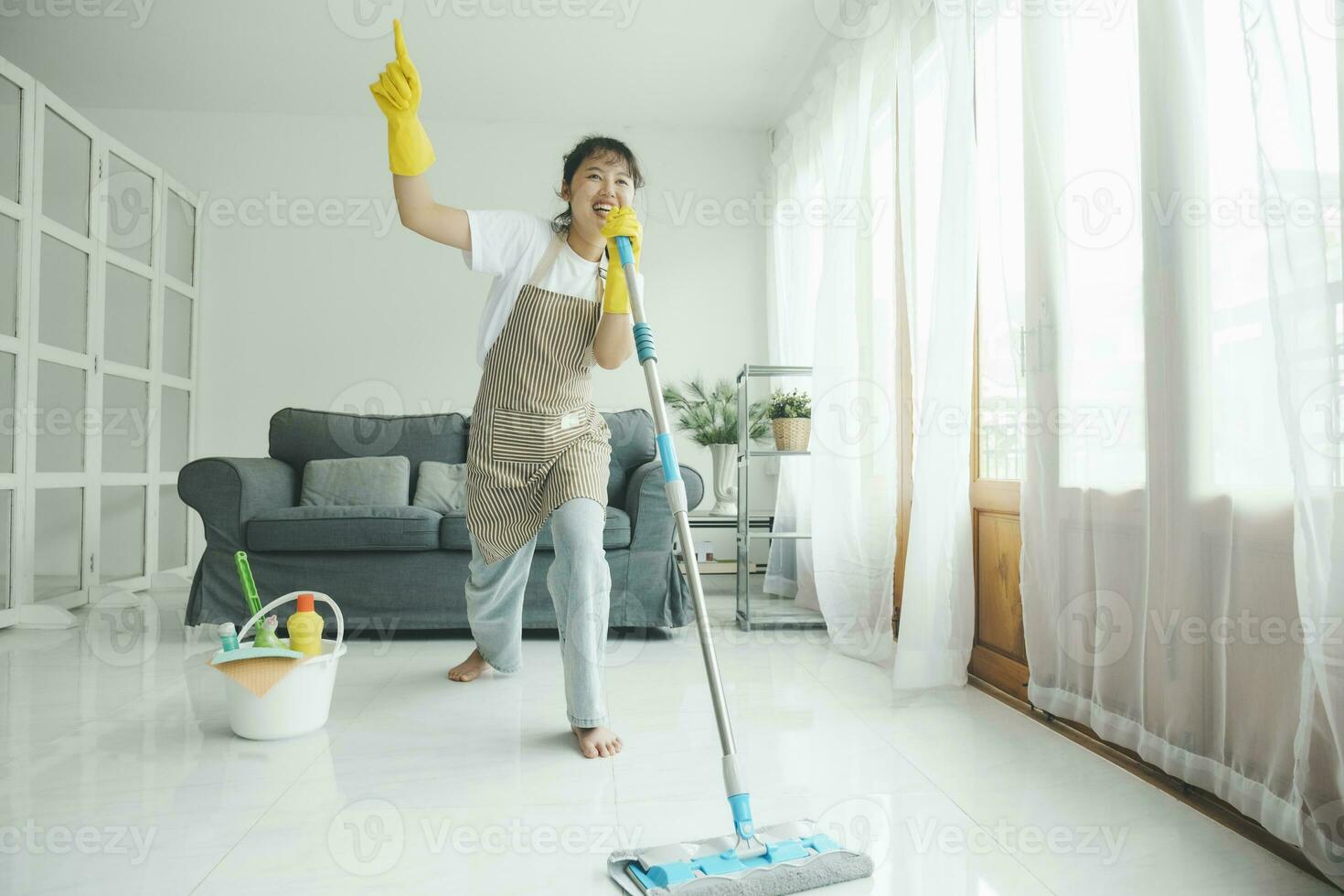 Young woman having fun while cleaning at home. photo