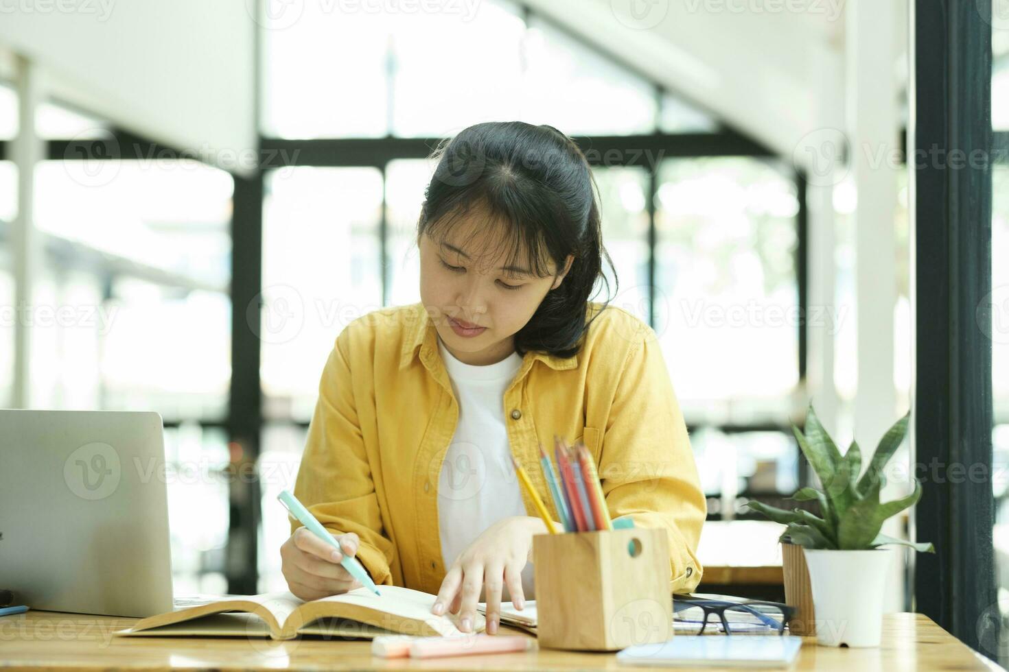 Serious young asian student reading a book preparing the exam. photo