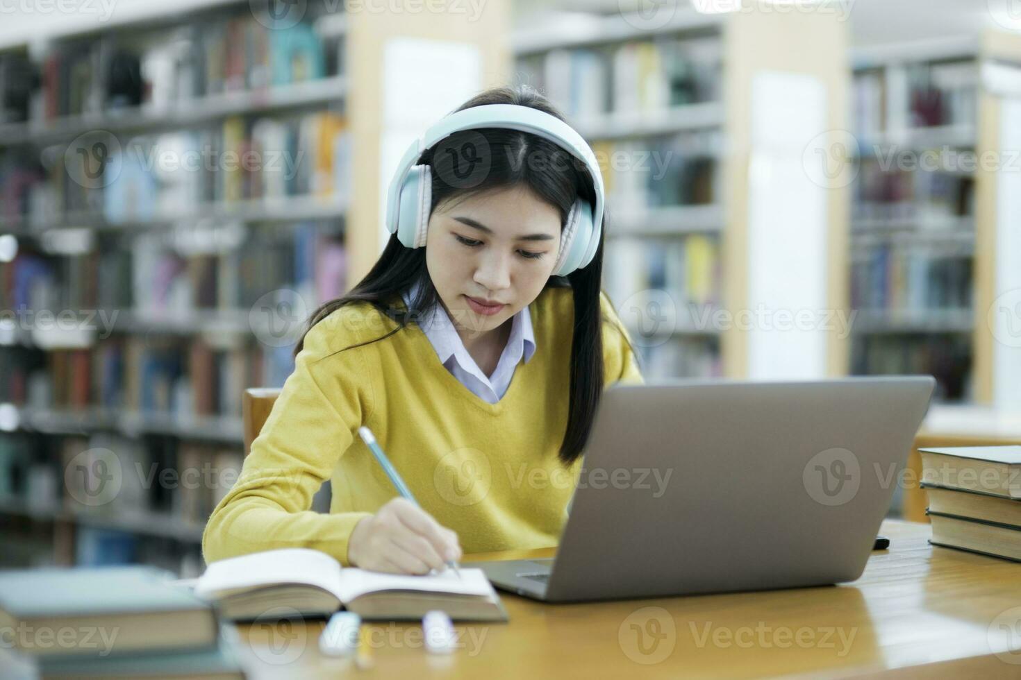 Student studying at library with laptop. photo