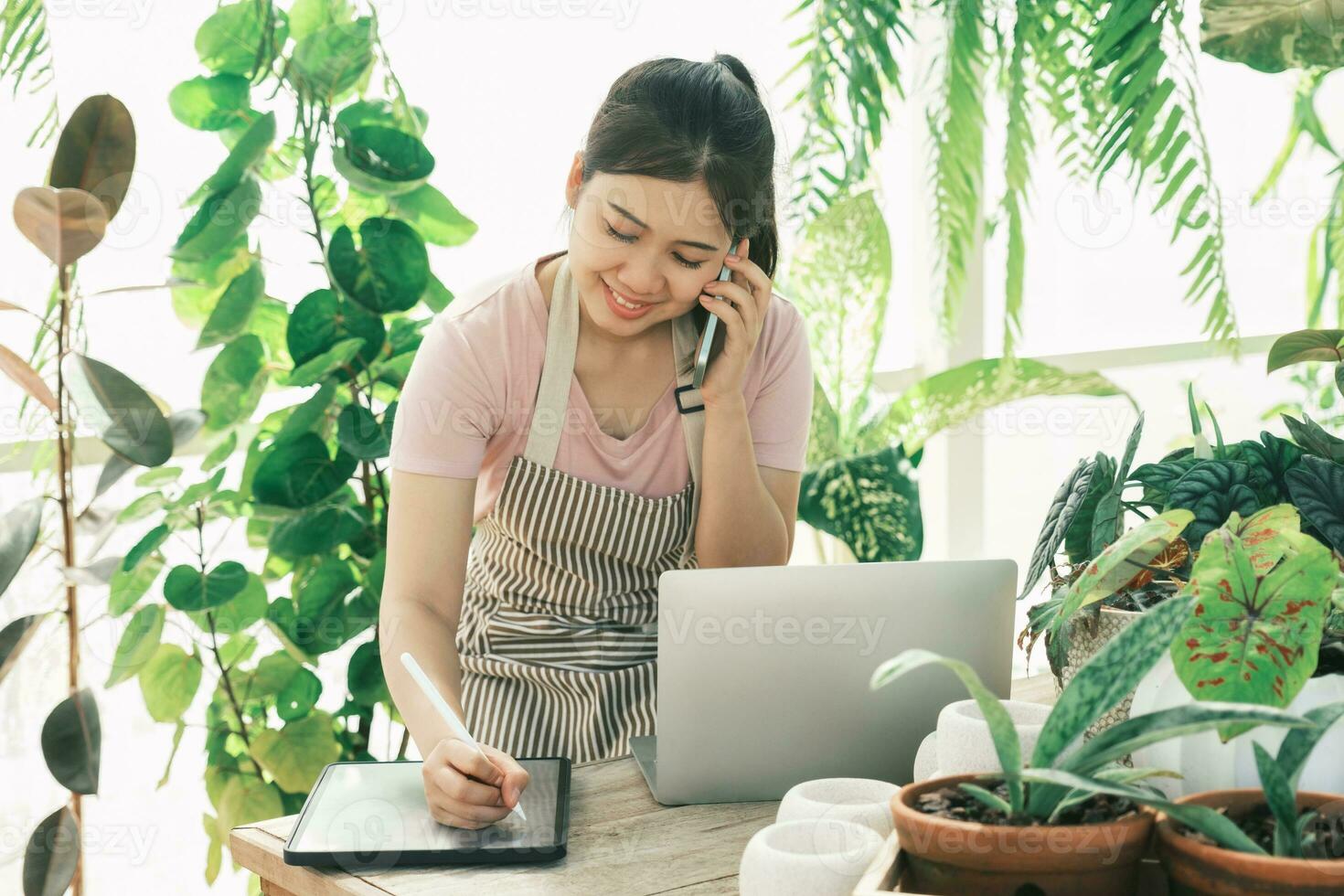 Young woman gardener is standing in the garden to contact customers. photo