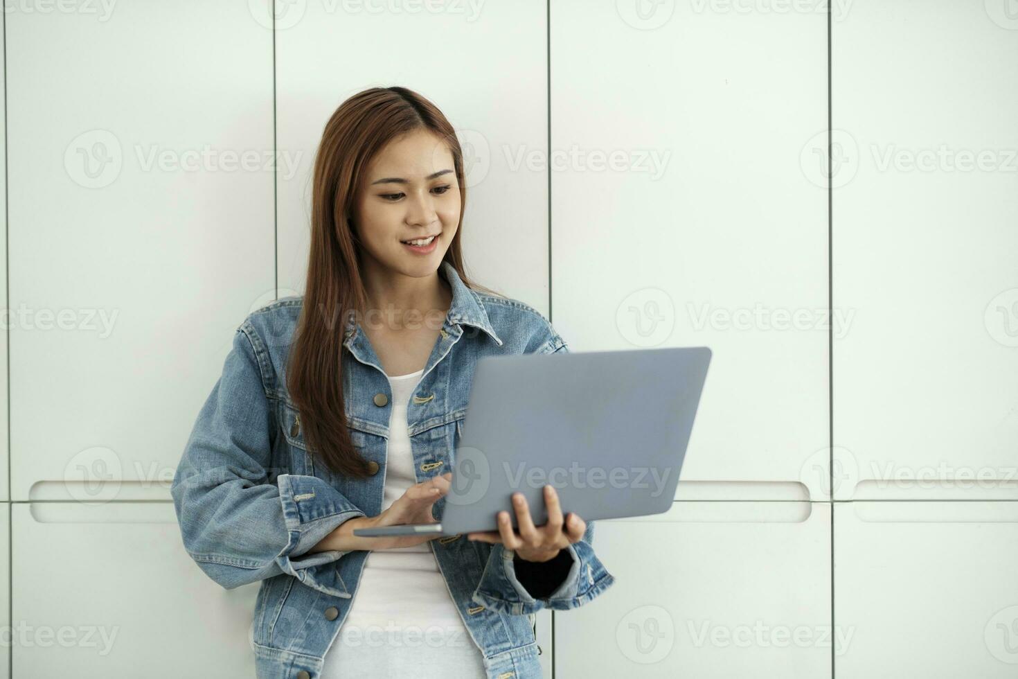 Young female student standing against wall online learning. photo