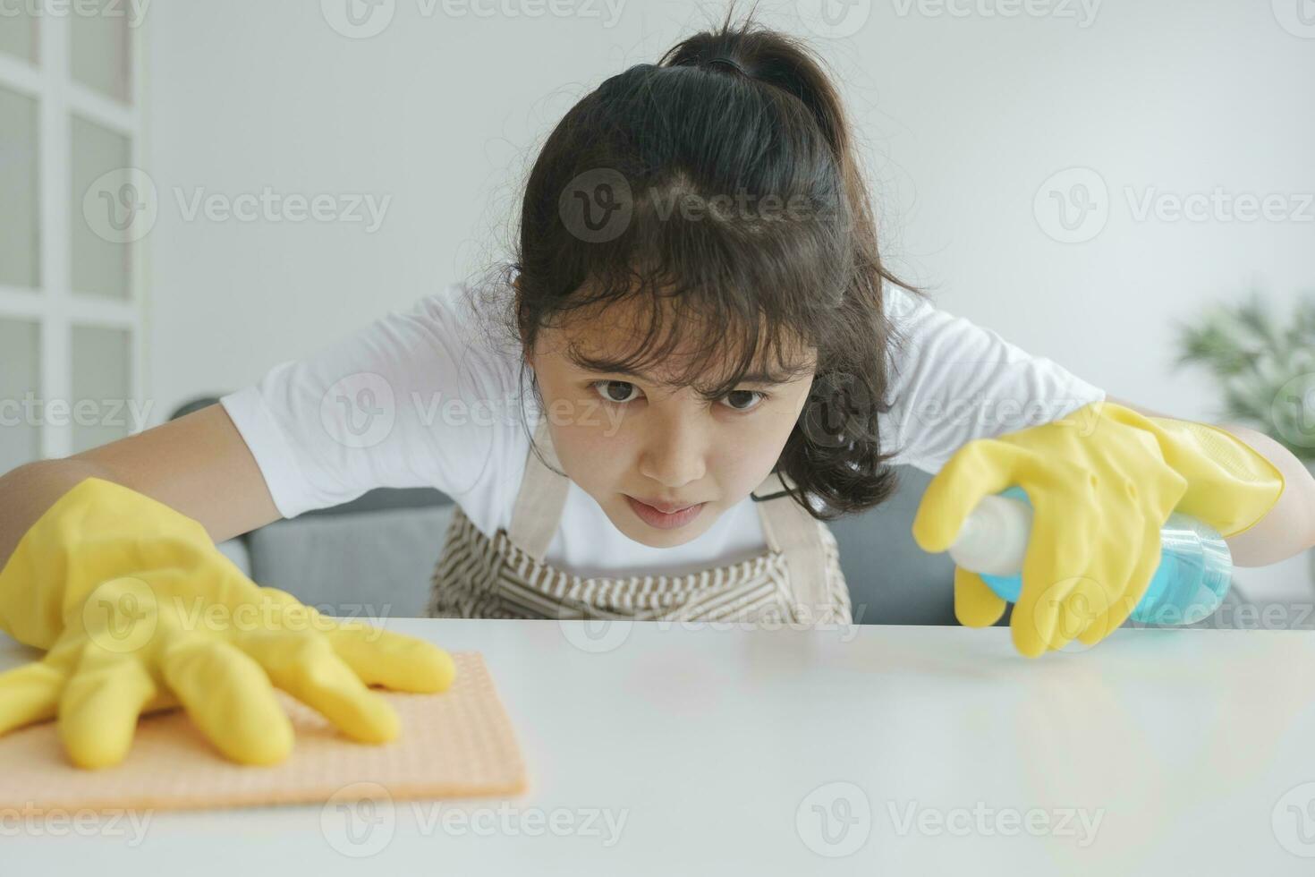 Young woman cleaning table wearing gloves at home. photo