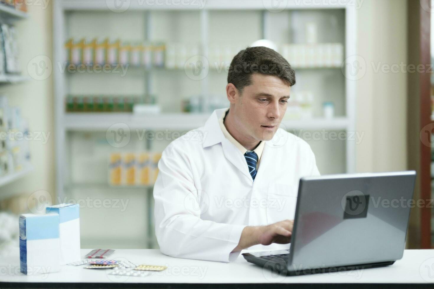 masculino farmacéutico trabajando en moderno farmacia utilizando ordenador portátil. foto