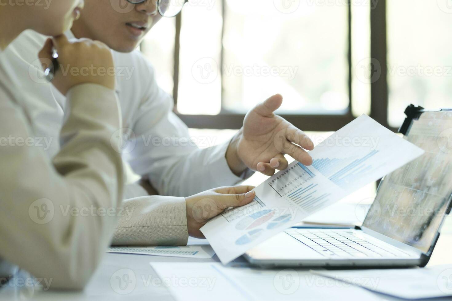 Close up businesspeople are working by discuss and analyses their project by using laptop and graphs. photo