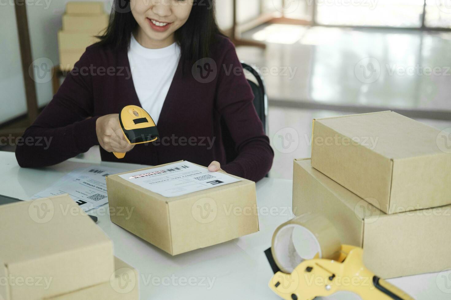 Female online business owner scan shipping label on parcel. photo
