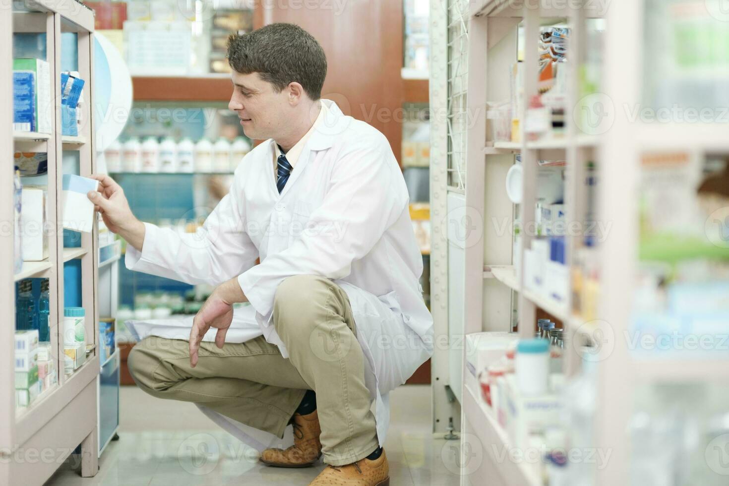 Male pharmacist checking stock inventory in pharmacy. photo