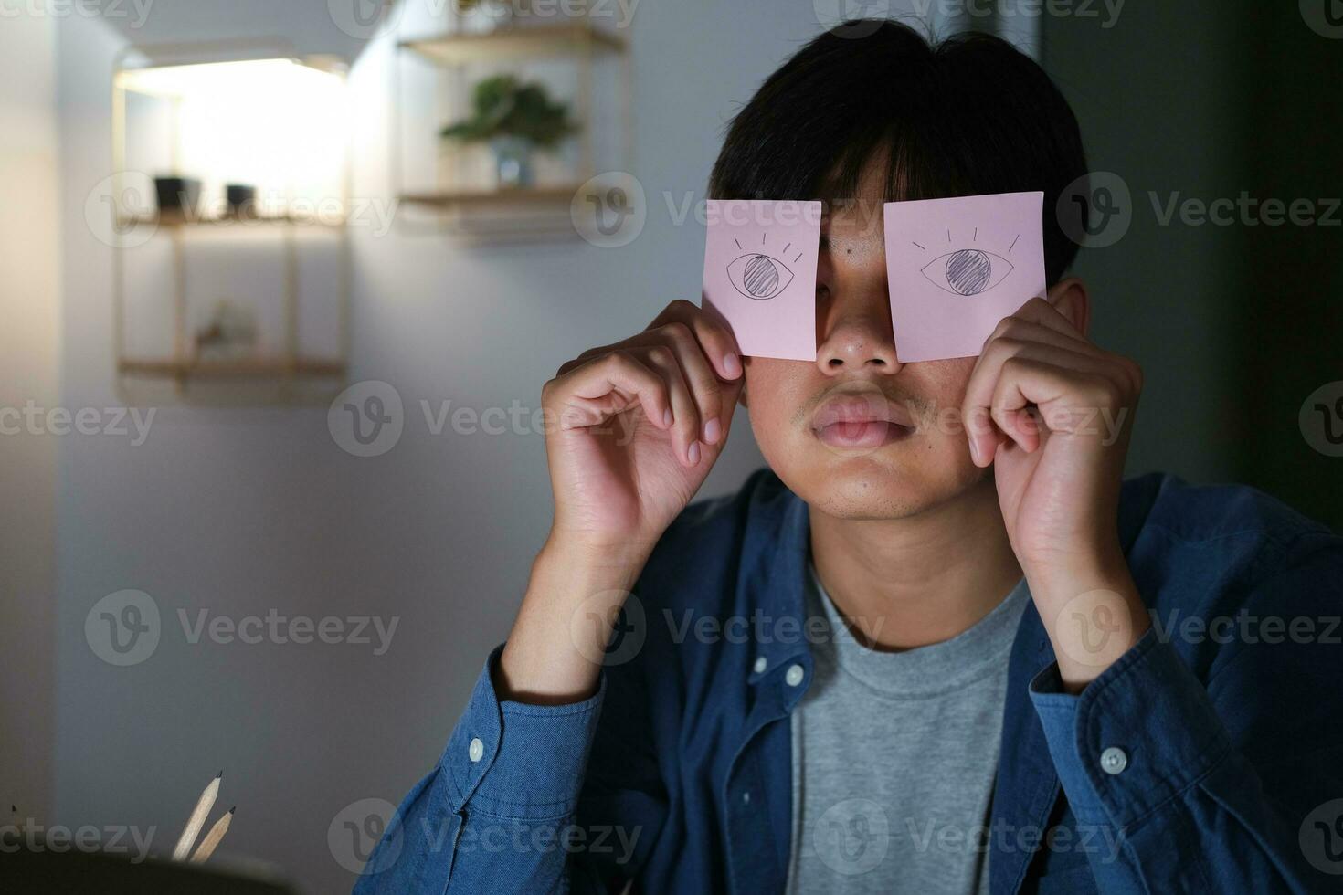 Exhausted tired workaholic young man with painted eyes on stickers photo