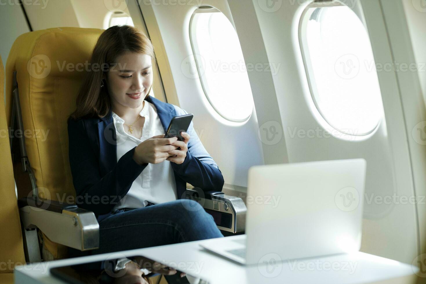 Business woman working using phone while sitting in airplane. photo