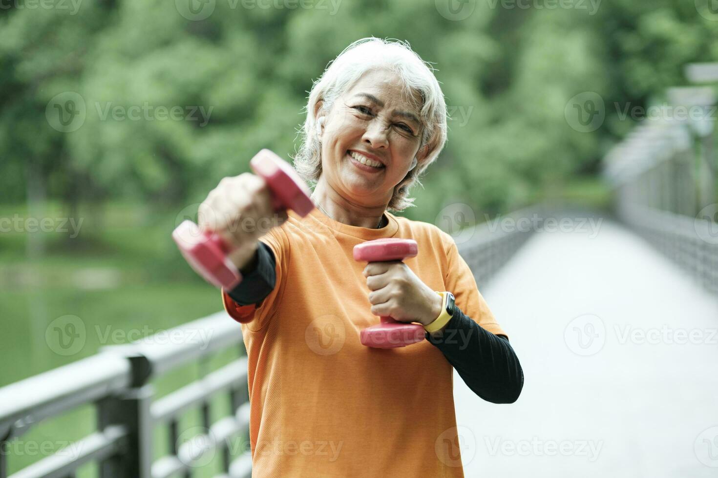 Athletic Senior woman lifts dumbbells while doing fitness. photo