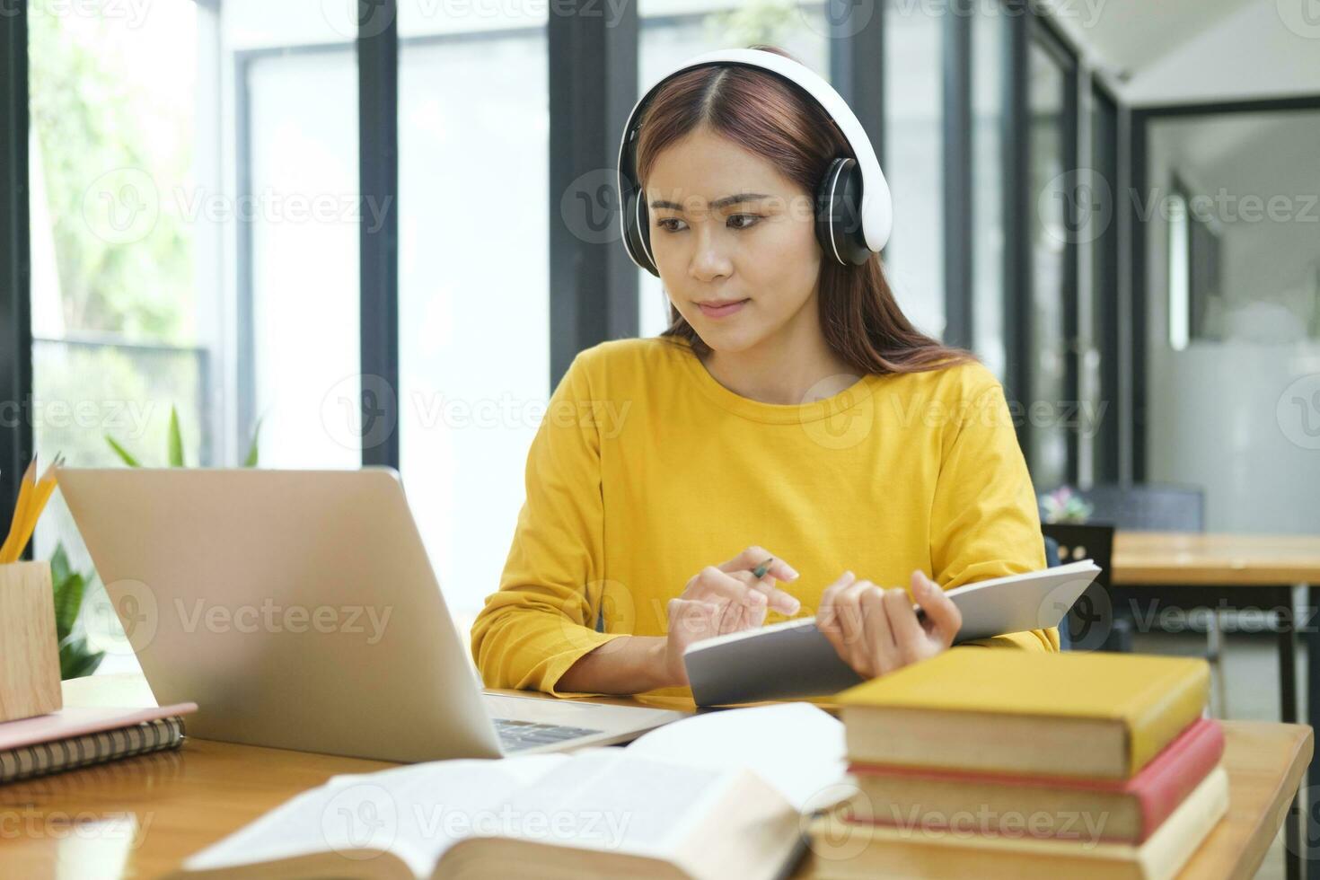 Woman learning online using laptop and writing notes. photo