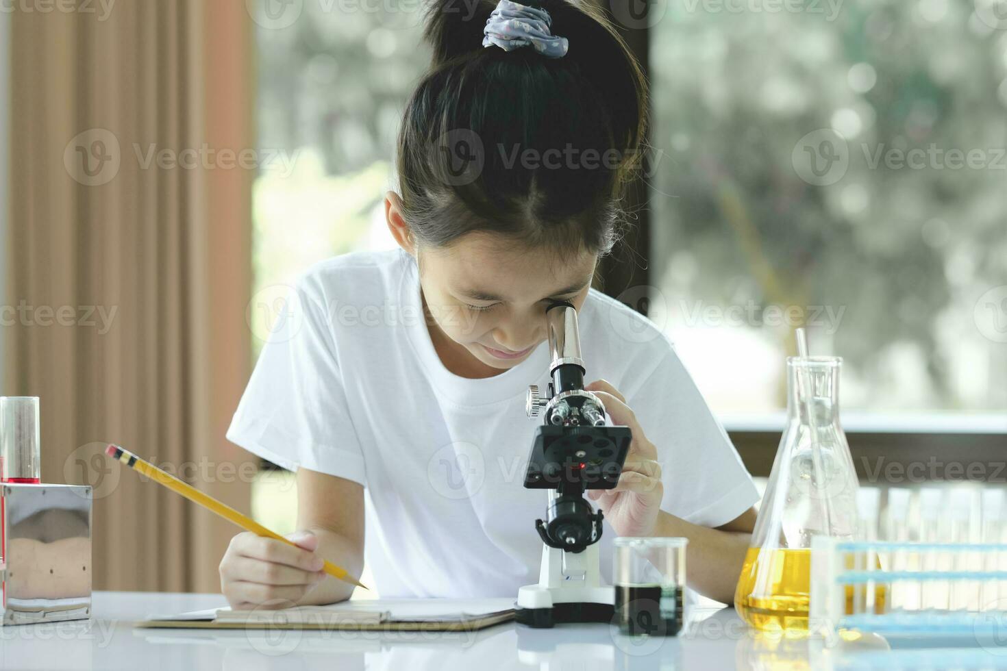 Little child with learning class in school laboratory using microscope photo