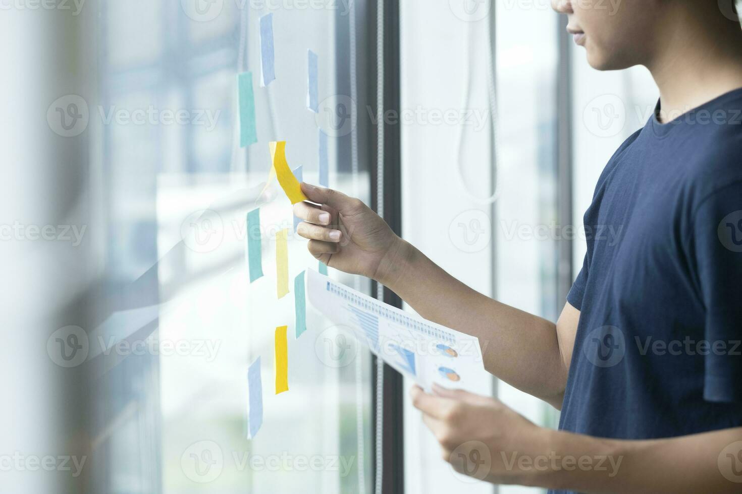 Creative man reading sticky notes on glass wall photo