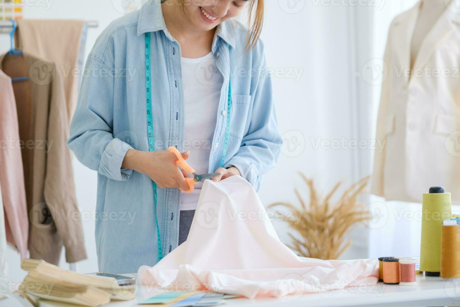 Close up of young asian female fashion designer is cutting fabric and prepare a pattern for a new collection. photo