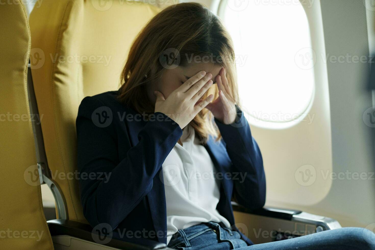 Businesswoman In a plane, covering her face with both hands with the stress. photo