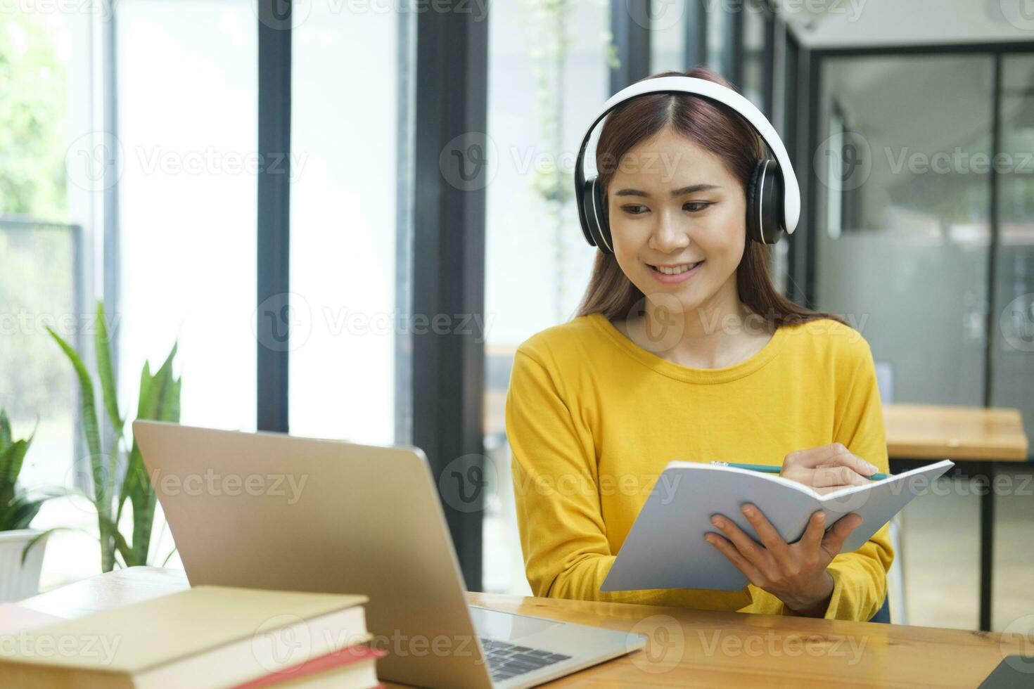 Woman learning online using laptop and writing notes. photo