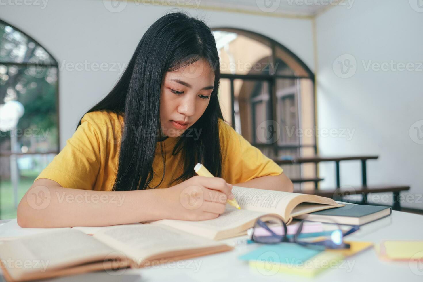 grave asiático hembra estudiante leyendo libros para examen preparación foto