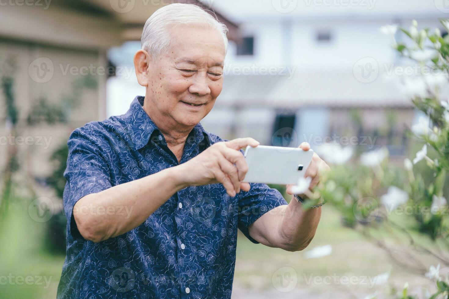 Happy asian senior man taking a picture with mobile phone. photo