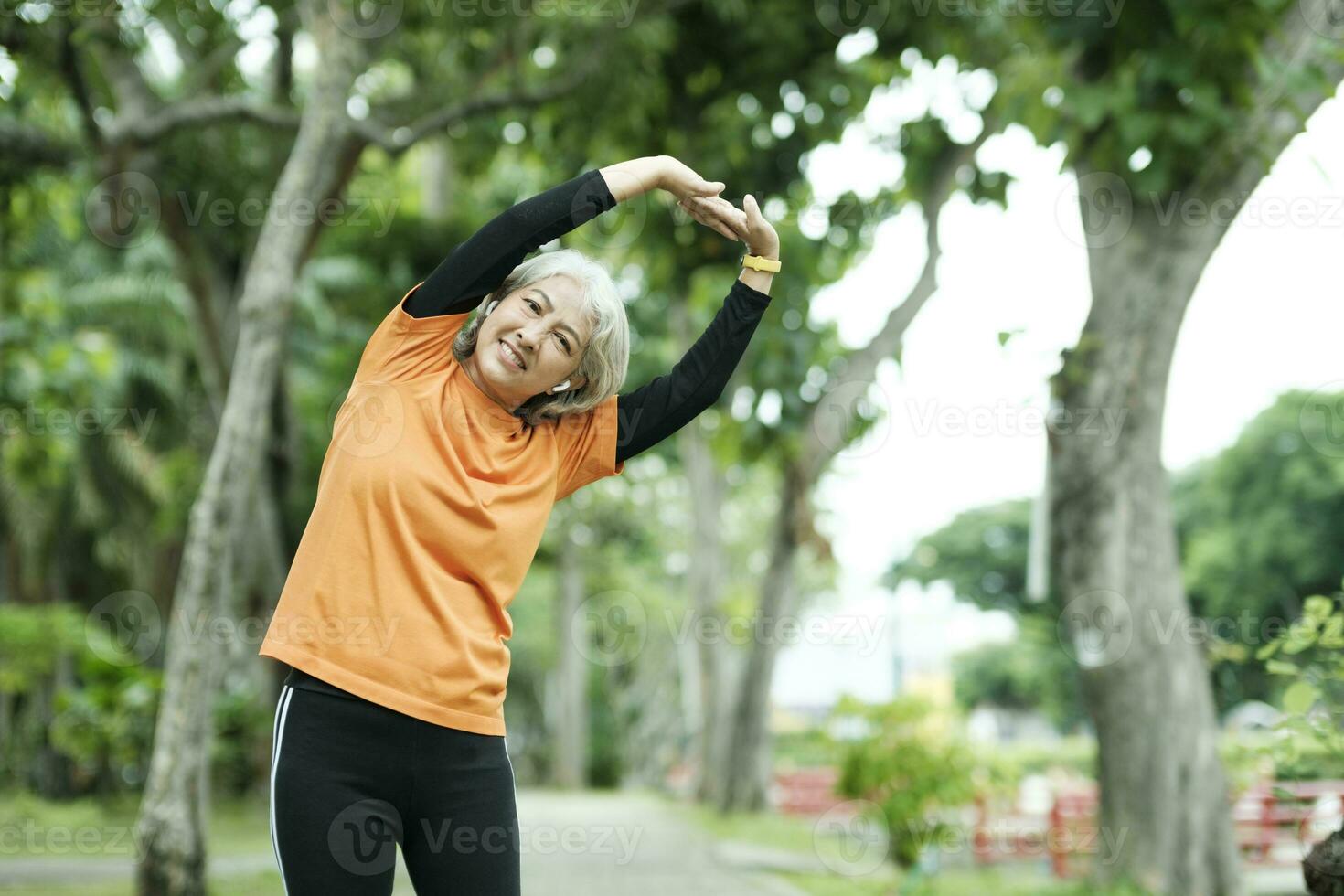 Athletic Senior woman stretching two arms in park. photo