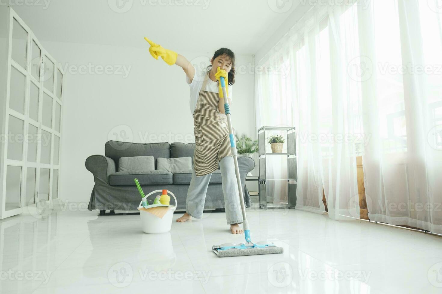 Young woman having fun while cleaning at home. photo