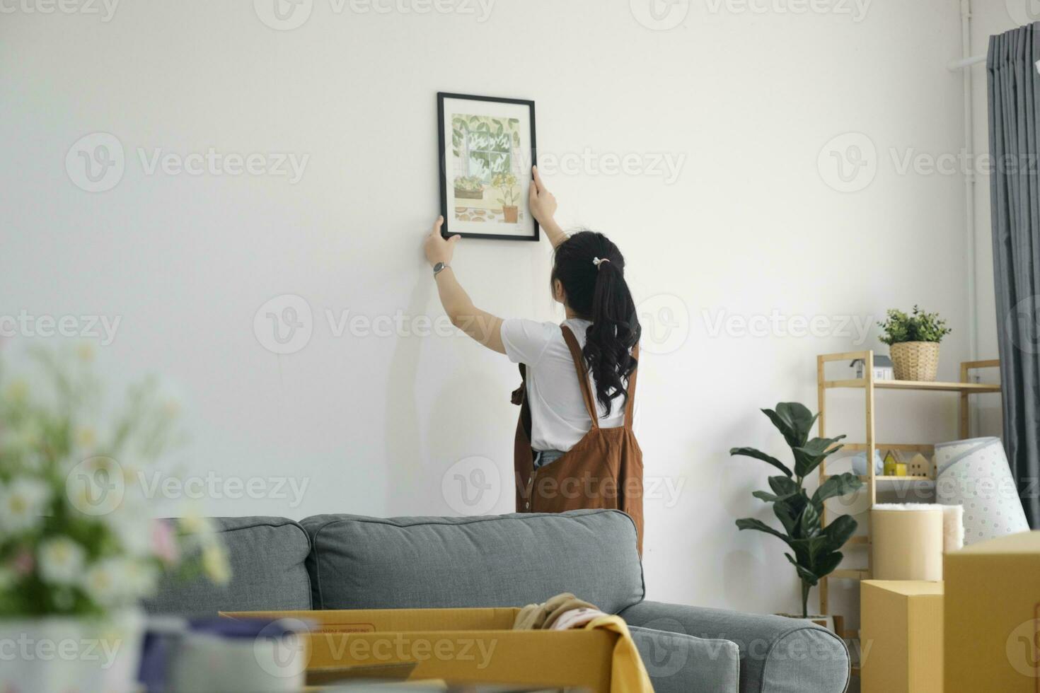 mujer decorando nuevo hogar mientras Moviente en a nuevo casa o departamento. foto