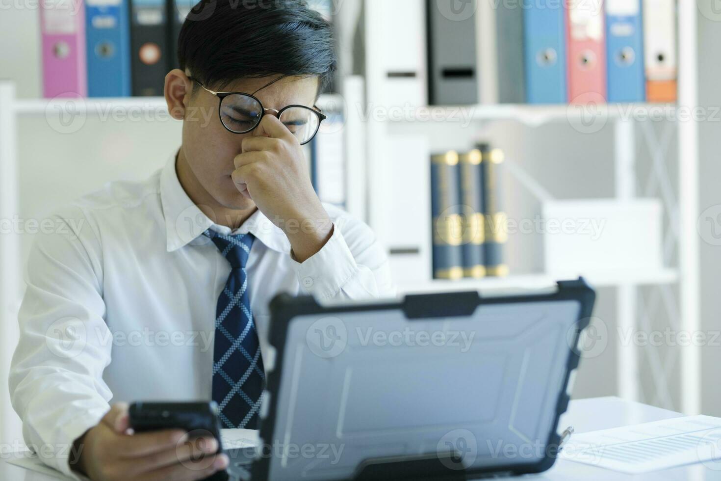 Tired and overworked manager sitting in front of computer and trying to concentrate, his eyes are dry and hurt. photo