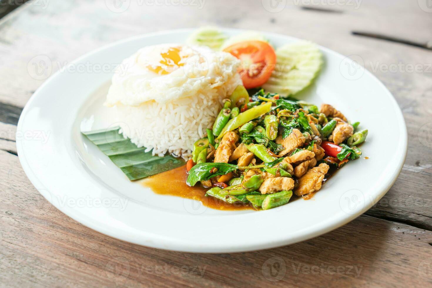 rice and stir fried chicken with basil and fried egg on top photo