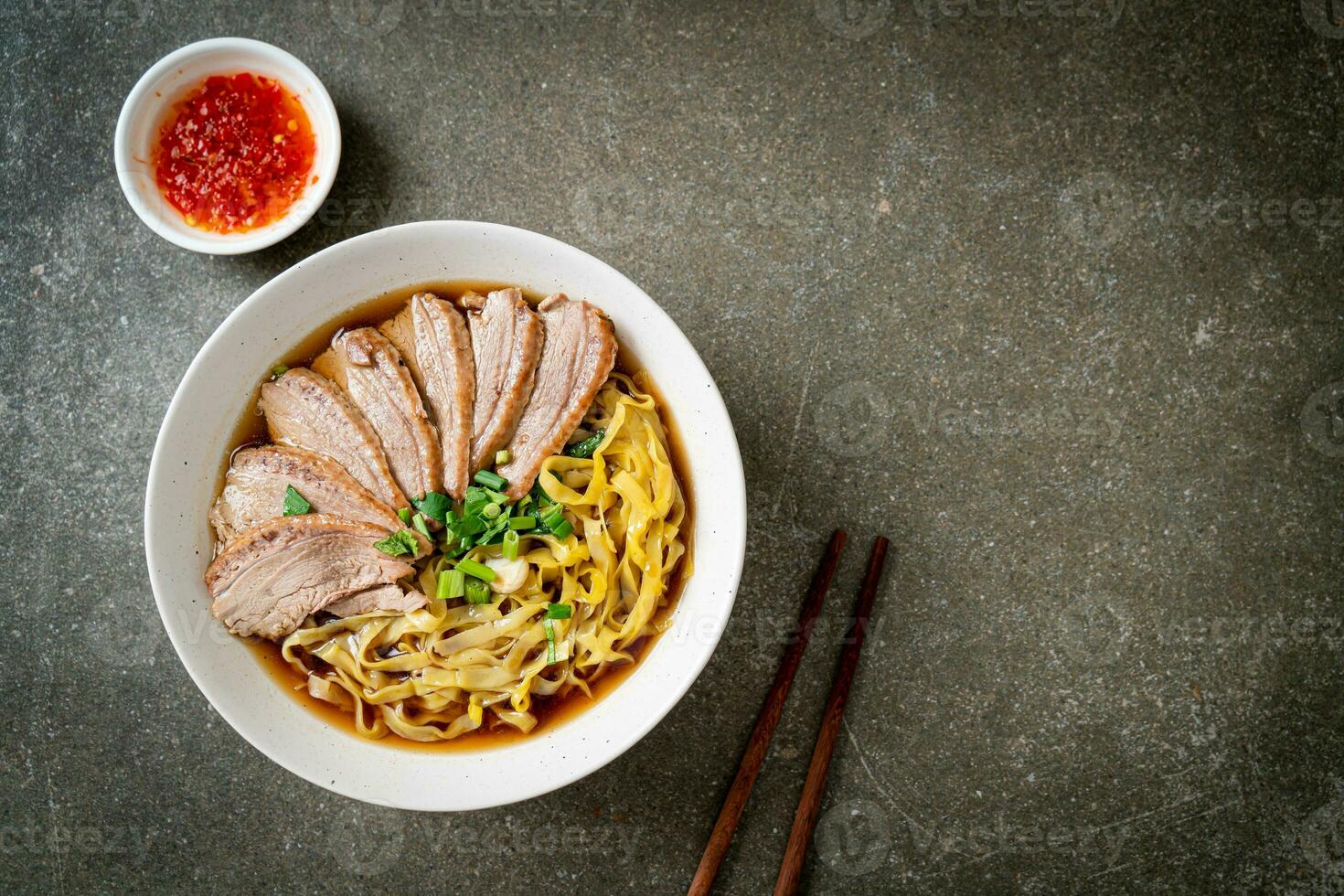 tallarines de huevo con pato guisado en sopa marrón foto