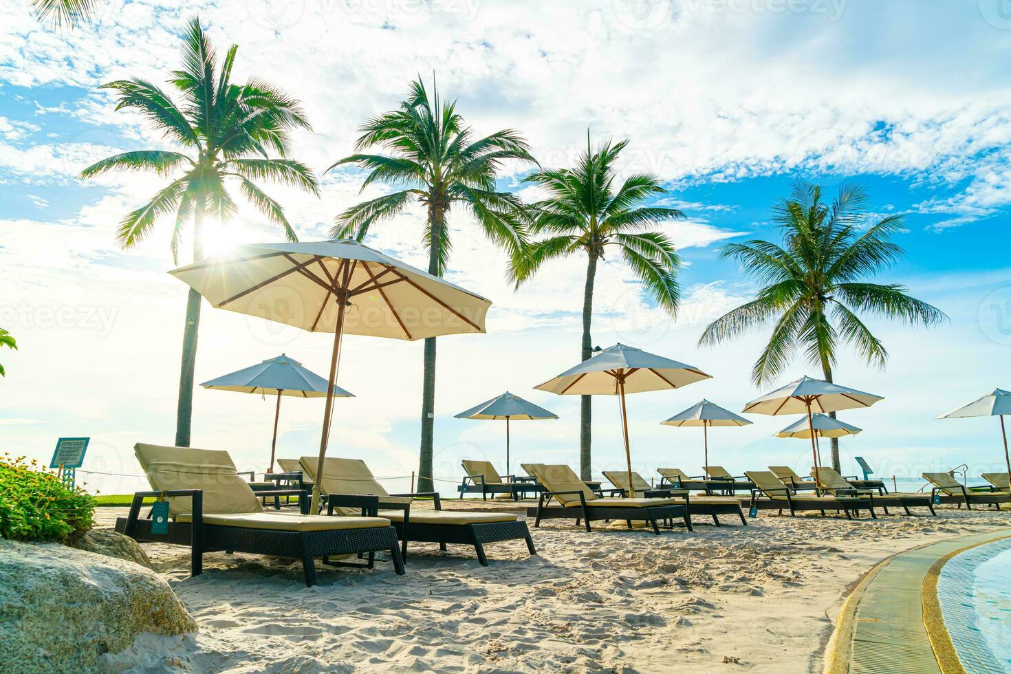 Beautiful luxury umbrella and chair around outdoor swimming pool in hotel and resort with coconut palm tree on sunset  or sunrise sky photo