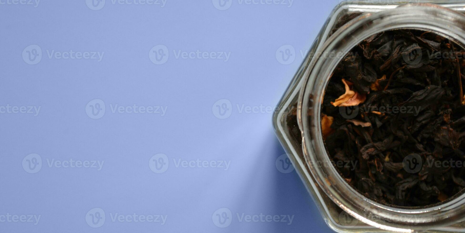 leaf tea with pieces of fruit in a jar, black tea, a jar of tea on a blue background, international tea day, banner, place for text photo