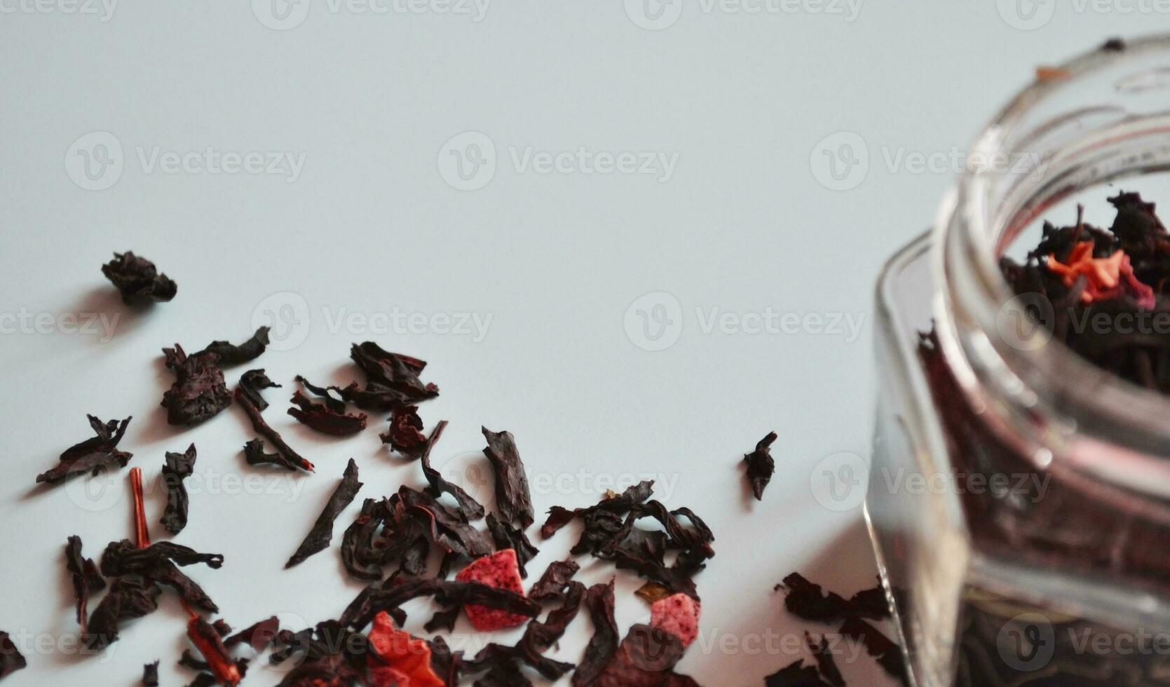 leaf tea with pieces of fruit in a jar, scattered tea, black tea, a jar of tea on a gray background, international tea day, banner photo