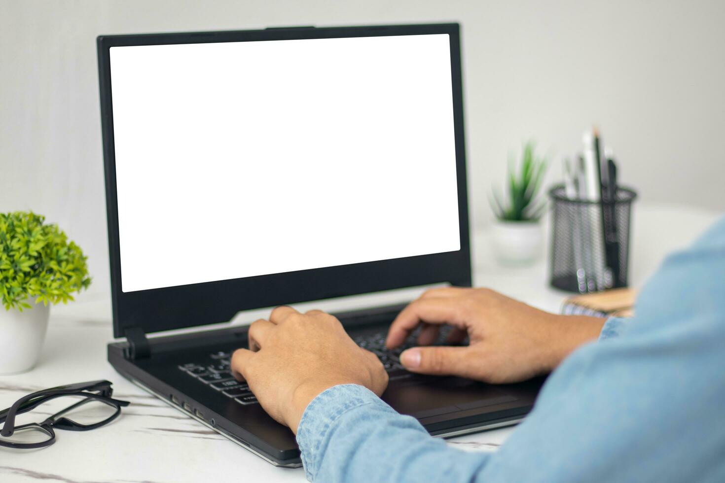 man's hands working on laptop in front of white photo