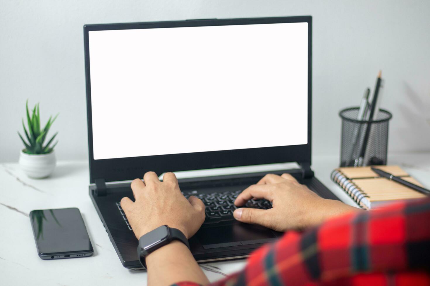 man's hands working on laptop in front of white photo