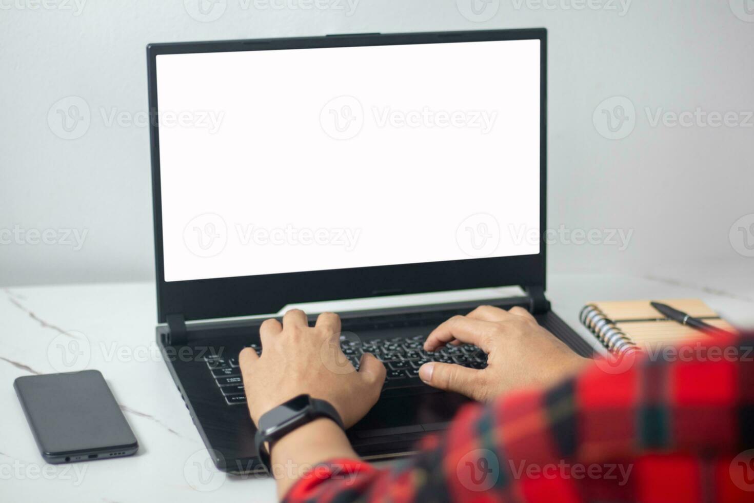 man's hands working on laptop in front of white photo